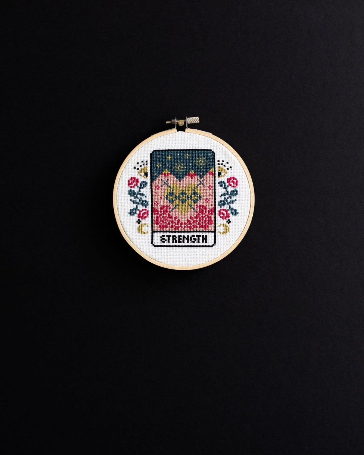 strength tarot cross stitch design on a black background