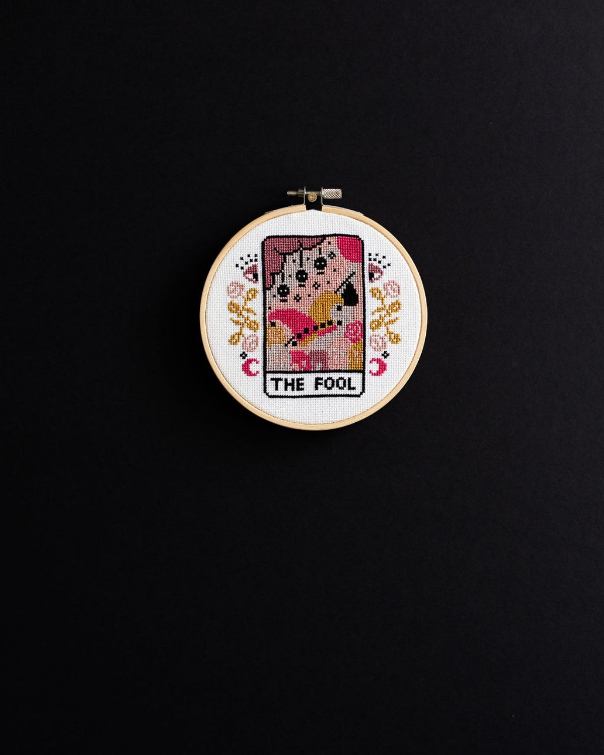 The fool tarot cross stitch design on a black background