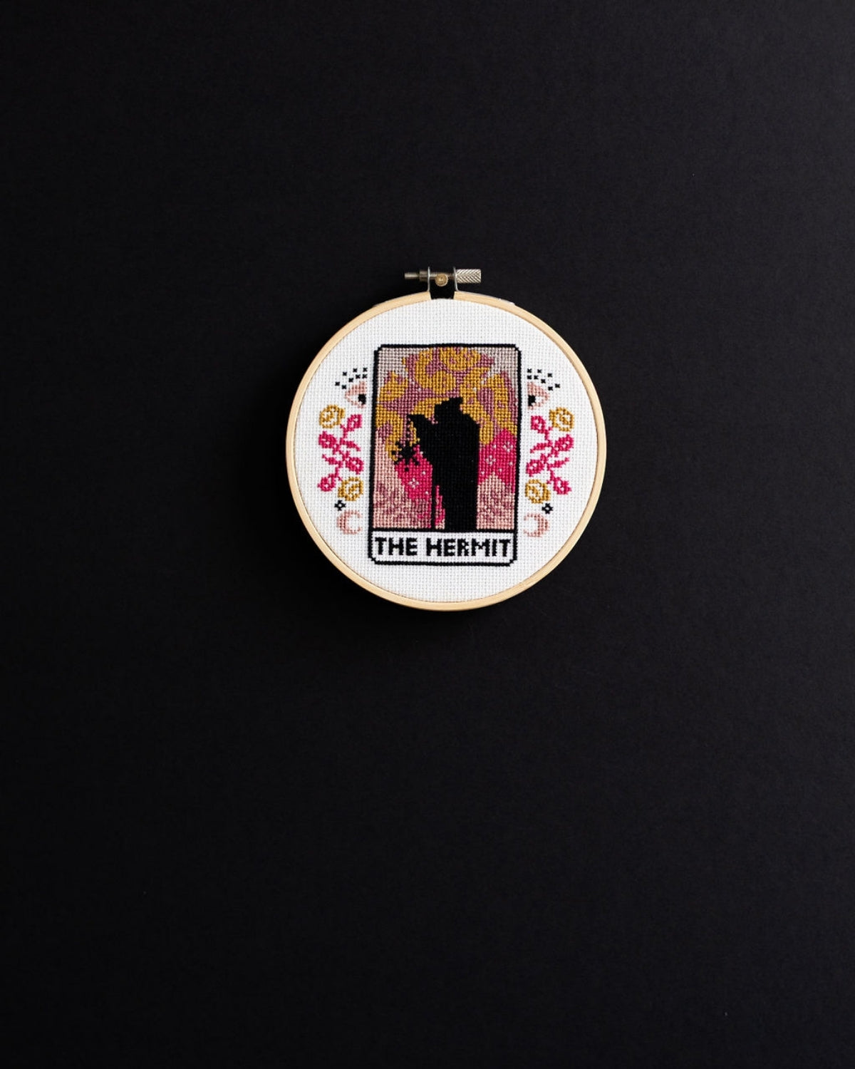 The hermit tarot cross stitch design on a black background