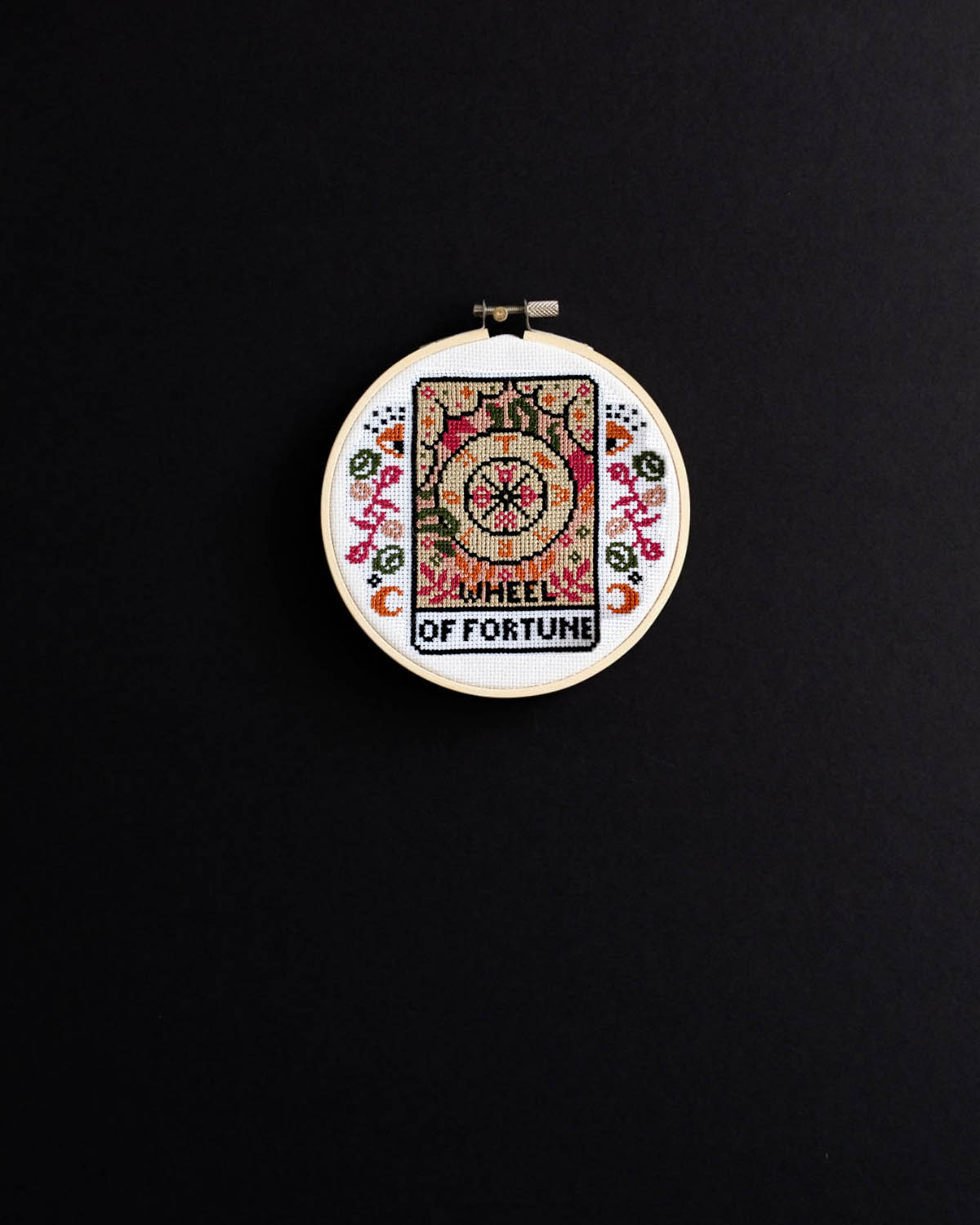 The wheel of fortune tarot cross stitch design on a black background